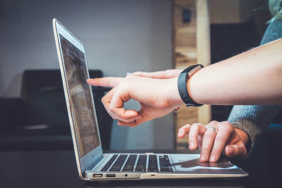 A person pointing at a computer screen displaying code